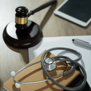 Tablet, gavel, stethoscope and folders, representing ethics in healthcare.