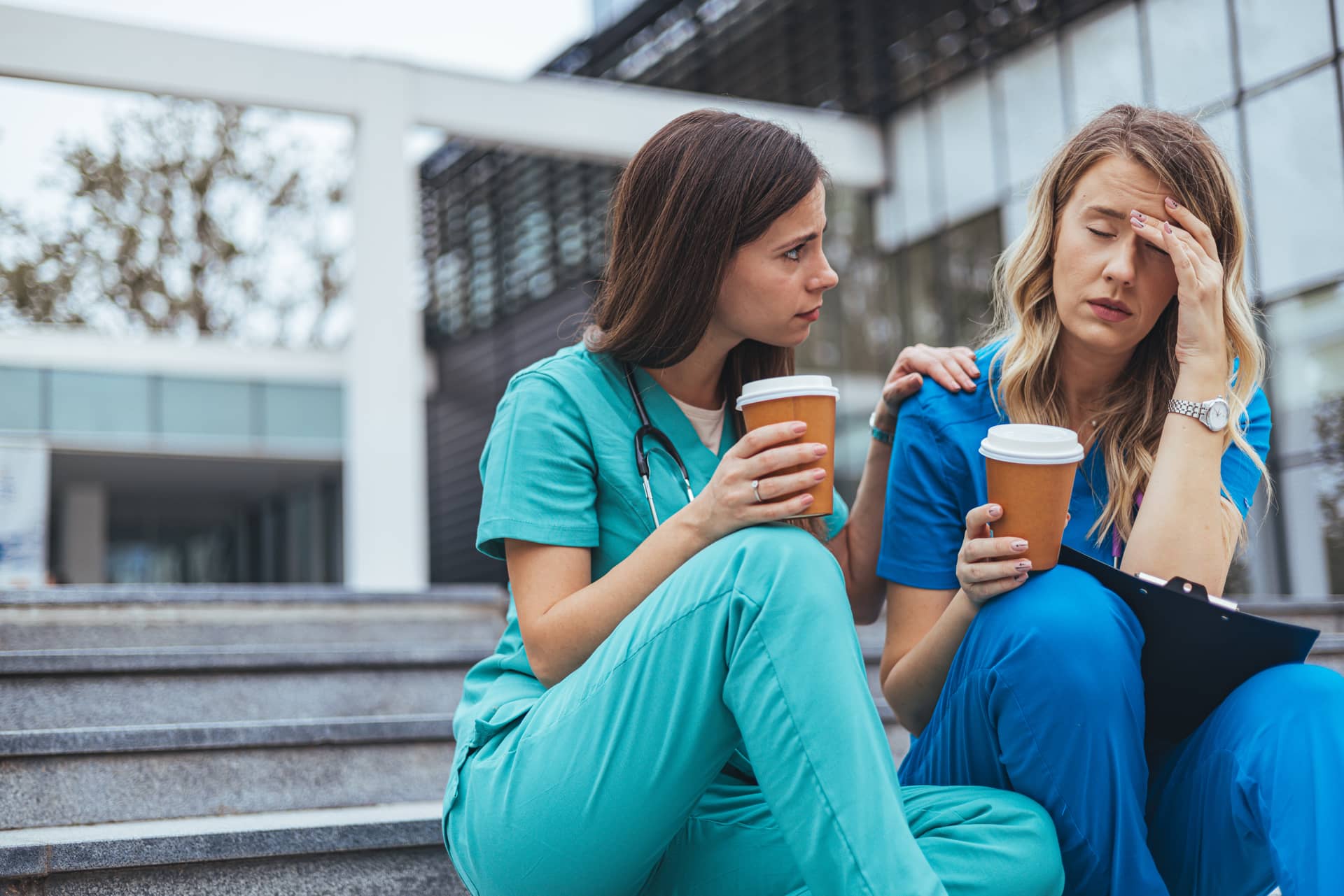 A nurse comforting another nurse who is stressed while on break outside the hospital