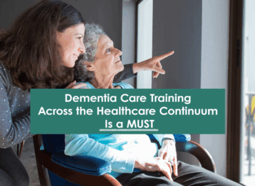 dementia-care-training Younger woman supporting and smiling with an older woman with dementia who is seated and pointing out a window, with a text overlay that reads “Dementia Care Training Across the Healthcare Continuum Is a MUST.”