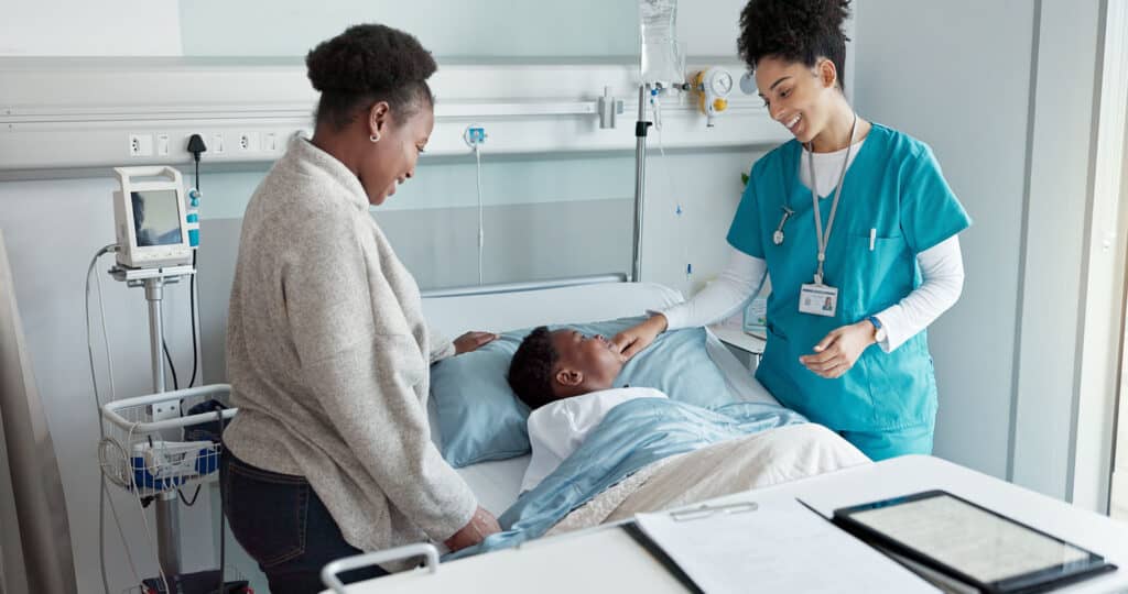 California CNA providing bedside care to pediatric patient in hospital setting, representing certified nursing assistant continuing education and renewal training.