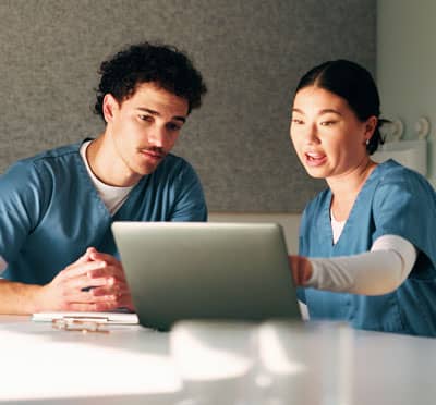 Healthcare team reviewing information on a laptop during a quality improvement discussion.