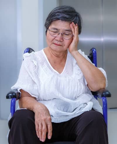 Older adult in a wheelchair experiencing discomfort, illustrating the importance of TBI training for California Assisted Living Waiver staff