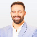 Zachary M. in a business suit on a white backdrop.