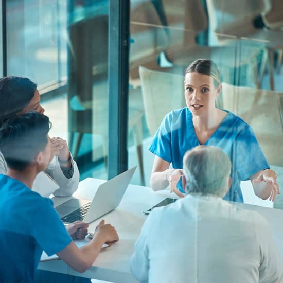 Case manager discussing a patient’s care plan with healthcare team members during a collaborative meeting.