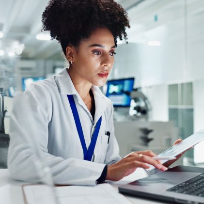 Public health professional analyzing data using a laptop and tablet in a laboratory setting