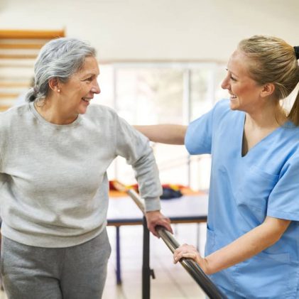 Skilled nursing rehabilitation staff member supporting an older adult with mobility, resident safety, and long-term care therapy services.